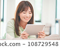 A woman watching videos on a tablet in the living room 108729548