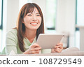 A woman watching videos on a tablet in the living room 108729549