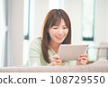 A woman watching videos on a tablet in the living room 108729550