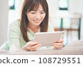A woman watching videos on a tablet in the living room 108729551