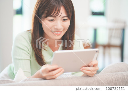 一位女士在客廳用平板電腦觀看視頻 108729551