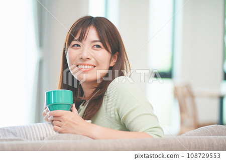 在客廳裡喝咖啡放鬆的女人 在客廳裡喝咖啡放鬆的女人 108729553