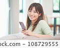 A woman who operates a smartphone in the living room 108729555