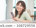 A woman who operates a smartphone in the living room 108729556
