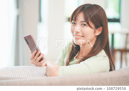 在客廳裡操作智能手機的女人 108729558