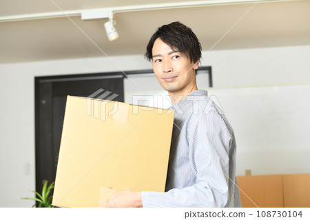 Young Asian man in casual clothes carrying a cardboard box Young Asian man in casual clothes carrying a cardboard box 108730104