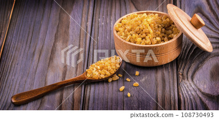 The Wooden scoop spoon and bowl full of brown cane sugar with pinch of sugar spilled around on wooden table, top view 108730493