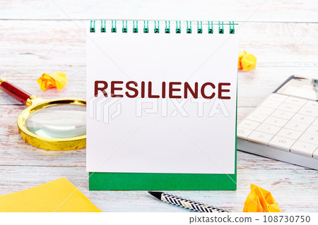 RESILIENCE text on the white sheet of the notebook is next to a magnifying glass, calculator, pencil, stickers RESILIENCE text on the white sheet of the notebook is next to a magnifying glass, calculator, pencil, stickers 108730750