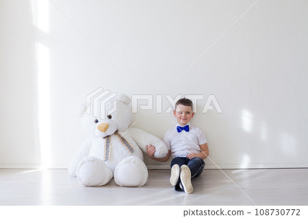 a boy sits in a bright room with a soft toy 108730772