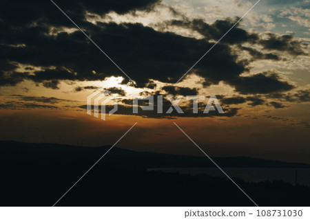 Abstract background sky Dawn Sunset Contrast dark shadow bright cloud sun orange silhouette above the mountains near the sea Abstract background sky Dawn Sunset Contrast dark shadow bright cloud sun orange silhouette above the mountains near the sea 108731030