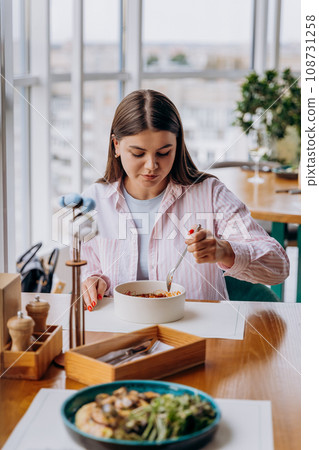 Young attractive woman enjoys tasty meal on cafe or restaurant background Young attractive woman enjoys tasty meal on cafe or restaurant background 108731258