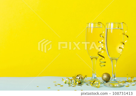Champagne glasses and christmas decor on colored holiday background. Flat lay New Year decorations 108731413