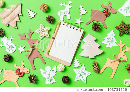 Christmas green background with holiday toys and decorations. Top view of notebook. Happy New Year concept 108731526