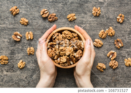 Woman hands holding a wooden bowl with walnut nuts. Healthy food and snack. Vegetarian snacks of different nuts 108731527