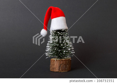 One small Christmas tree with santa hat on colored background. new year decoration with copy space 108731551