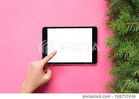 people and technology concept, close up of female hands pointing finger to tablet. blank screen on pink background, top view 108731636