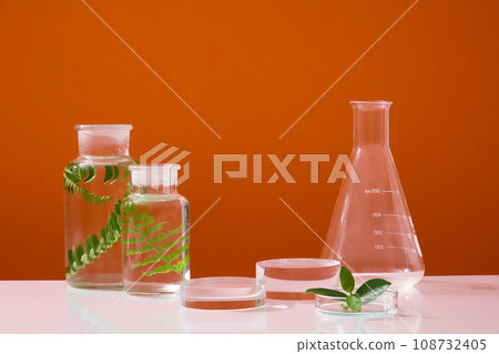 A flat-bottom florence flask arranged with two jars and a petri dish. Gallery geometric blank product stands for cosmetic product presentation. Orange background 108732405