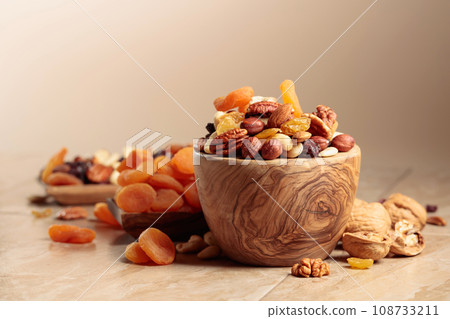 Dried fruits and nuts on a beige ceramic table. Dried fruits and nuts on a beige ceramic table. 108733211