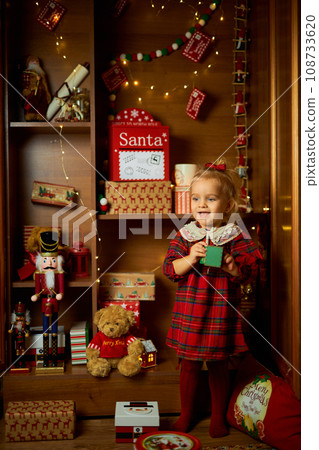 Merry Christmas and Happy Holiday. A little girl in a plaid dress 108733620