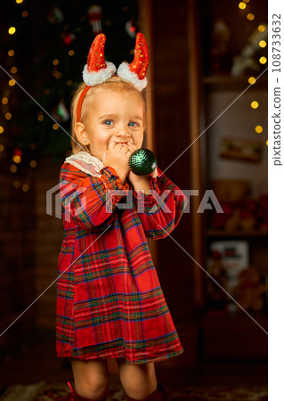 Little girl wearing Santa suit and red horns against white background 108733632