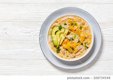 white chicken chili with cheese, avocado in bowl white chicken chili with cheese, avocado in bowl 108734549
