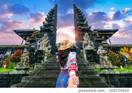 Women tourists holding man's hand and leading him to Besakih temple in Bali, Indonesia. 108734820