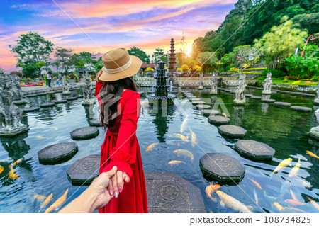 Women tourists holding man's hand and leading him to Tirta Gangga Water Palace in Bali, Indonesia. 108734825