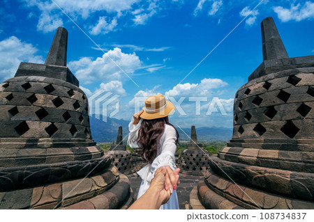 Women tourists holding man's hand and leading him to Borobudur Temple in Java Indonesia. 108734837