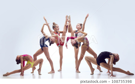 Little flexible girls, rhythmic gymnast athletes training in elegant stage costumes against white studio background 108735398