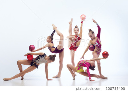 Group of beautiful little girls, children, rhythmic gymnasts in stage clothes dancing with balls against white studio background 108735400