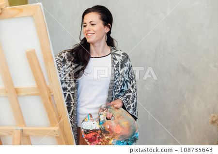 a female artist stands at an easel with a white canvas on a gray background a female artist stands at an easel with a white canvas on a gray background 108735643