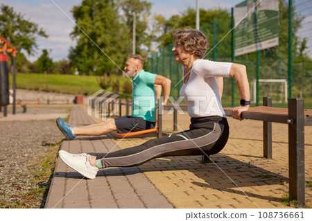 Happy sportive elderly couple training outdoors at playground Happy sportive elderly couple training outdoors at playground 108736661
