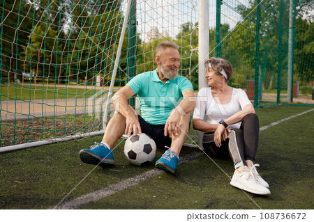Happy smiling and tired seniors couple resting after successful soccer training 108736672