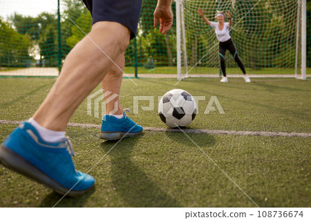 Happy retired people playing football together outdoors at city court Happy retired people playing football together outdoors at city court 108736674