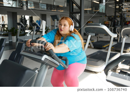 Tired young woman with obesity on treadmill during training workout Tired young woman with obesity on treadmill during training workout 108736740
