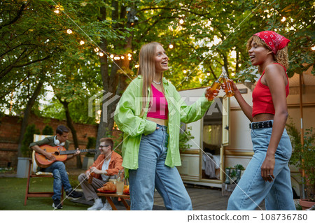 Little drunk two millennial females hugging and dancing, outdoor picnic with friends 108736780