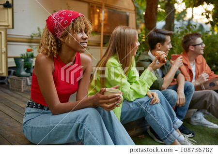 Happy group of friend sitting in row eating snacks rest during picnic Happy group of friend sitting in row eating snacks rest during picnic 108736787