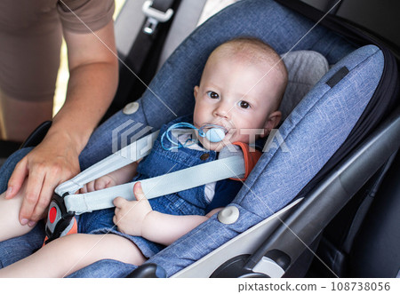 A little handsome boy sits in a child car seat tied with a seat belt. The concept of safety when transporting children in a car. 108738056
