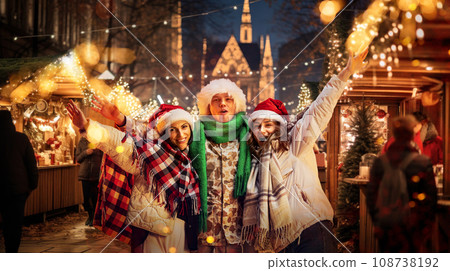Happy young people, man and women celebrating Christmas, visiting winter street fair and having fun outdoors. 108738192