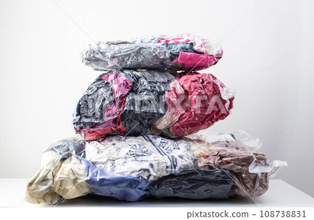 Multi-colored clothes and things packed in vacuum bags for storage on a white background. Modern compact storage technology, close-up Multi-colored clothes and things packed in vacuum bags for storage on a white background. Modern compact storage technology, close-up 108738831