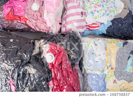 Background of vacuum bags with colorful clothes for storing compact size items. Modern technology, close-up Background of vacuum bags with colorful clothes for storing compact size items. Modern technology, close-up 108738837