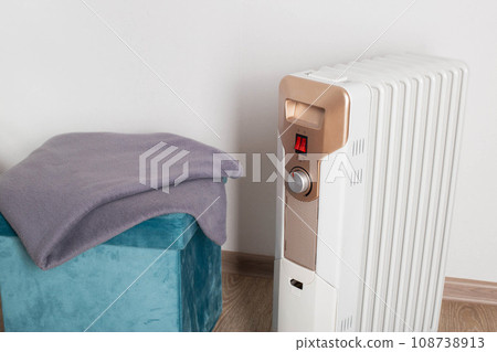 Electric heater on a white background next to a warm blanket. The concept of fire safety during the cold period when using an electric heater. Copy space for text, industry Electric heater on a white background next to a warm blanket. The concept of fire safety during the cold period when using an electric heater. Copy space for text, industry 108738913