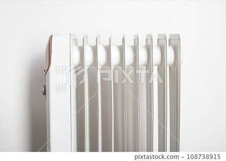 Modern electric oil heater on a white background. Heating the room. Heating season in apartments, close-up Modern electric oil heater on a white background. Heating the room. Heating season in apartments, close-up 108738915