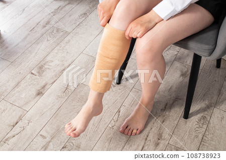Orthopedic medical kneecap on the leg of a girl. Fixation and support of the knee joint after injury. Orthopedic medical kneecap on the leg of a girl. Fixation and support of the knee joint after injury. 108738923