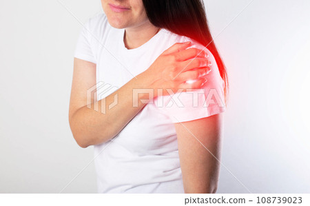 A girl has pain in her shoulder due to a pinched nerve in the cervical spine, osteochondrosis of the spine. Referred pain, close-up, myofascial syndrome A girl has pain in her shoulder due to a pinched nerve in the cervical spine, osteochondrosis of the spine. Referred pain, close-up, myofascial syndrome 108739023