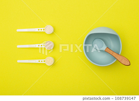 A blue children's plate with a spoon and a set of different dairy-free cereals for children's first feeding. Vitamin-mineral cereals for children, gluten-free, close-up 108739147