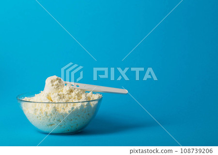 Plate with dry milk mixture enriched with vitamins, minerals and bifidobacteria on a blue background. Copy space for text Plate with dry milk mixture enriched with vitamins, minerals and bifidobacteria on a blue background. Copy space for text 108739206
