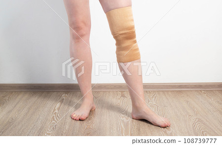 Orthopedic medical kneecap on the leg of a girl. Fixation and support of the knee joint after injury. Orthopedic medical kneecap on the leg of a girl. Fixation and support of the knee joint after injury. 108739777