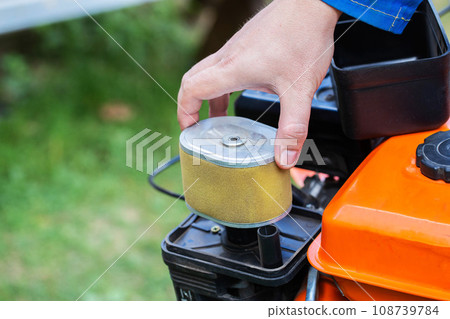 replacement of the air filter in the motoblock, service maintenance of agricultural machinery.Industry, walk-behind tractor. Copy space for text replacement of the air filter in the motoblock, service maintenance of agricultural machinery.Industry, walk-behind tractor. Copy space for text 108739784