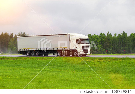 A truck with a semi-trailer transports cargo in summer in cloudy rainy weather on a wet road in the rain. Skidding on the road. Import substitution, export and import of goods. Trucking business, A truck with a semi-trailer transports cargo in summer in cloudy rainy weather on a wet road in the rain. Skidding on the road. Import substitution, export and import of goods. Trucking business, 108739814